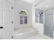 Bathroom featuring a soaking tub under an arched window, alongside a glass-enclosed shower at 840 Coach Lamp Ct, Sanford, FL 32771
