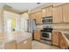 Well-lit kitchen features wooden cabinets, stainless steel appliances, and tile flooring at 2703 Gullane Ct, Kissimmee, FL 34746