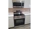 Stainless steel oven and microwave paired with white cabinets and modern countertops, complimented by wood-look floors at 2221 The Oaks Blvd, Kissimmee, FL 34746