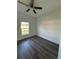 Bedroom with window, ceiling fan, dark wood-look floors, and bright white walls at 5115 Old Highway 37, Lakeland, FL 33811