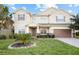 Charming two-story home featuring a well-manicured lawn, stone accents, and a welcoming entrance at 1387 Lexington Ave, Davenport, FL 33837