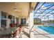 Inviting covered patio with a ceiling fan, outdoor seating and a view of the pool and lake beyond at 1387 Lexington Ave, Davenport, FL 33837