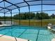 Screened pool with a beautiful view of the lush green trees surrounding the serene lake at 1387 Lexington Ave, Davenport, FL 33837