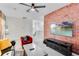 Modern living room with a brick accent wall, TV, ceiling fan, and comfortable seating at 4348 Quote St, Kissimmee, FL 34746