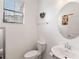 The bathroom features a toilet, a sink, a round mirror, and a window at 8541 Spyglass Ln, Davenport, FL 33896