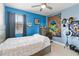 Bedroom featuring blue walls, a ceiling fan, a window, and bed with a patterned comforter at 8541 Spyglass Ln, Davenport, FL 33896