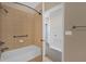 A tiled bathroom with a tub and shower, featuring a doorway leading to the adjacent hallway at 2774 Bella Vista Dr, Davenport, FL 33897