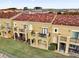 Rear view of tan two-story townhomes with balconies and a lush green lawn at 2774 Bella Vista Dr, Davenport, FL 33897