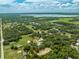 Expansive aerial view showcases the property and its natural surroundings, including lush greenery and a serene lake in the distance at 4450 Kaiser Ave, St Cloud, FL 34772