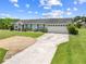 Single story home with light exterior, blue shutters, gravel and paved driveways, and attached garage at 720 Shore Drive, Kissimmee, FL 34744