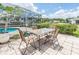 Outdoor patio set with view of screened pool and sunny yard with green space and blue skies at 720 Shore Drive, Kissimmee, FL 34744