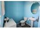 Small powder room with pedestal sink, toilet, and light blue walls at 1401 Hollow Creek Ln, Kissimmee, FL 34744