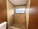 Tiled bathroom featuring a walk-in shower with updated fixtures and a window for natural light at 3180 Owassa Ct, Kissimmee, FL 34746