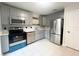 Modern kitchen boasts stainless steel appliances, stylish gray cabinets, and clean white tile flooring at 3180 Owassa Ct, Kissimmee, FL 34746