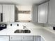 Modern kitchen features gray cabinets, stainless steel sink and white quartz countertops at 3180 Owassa Ct, Kissimmee, FL 34746