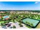 Aerial view of a neighborhood highlighting a pool, tennis courts, a parking lot and mature trees at 6012 Oak Green Loop, Davenport, FL 33837