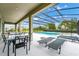 A covered patio provides an abundance of outdoor seating and overlooks the inviting screened-in pool area and green spaces at 6012 Oak Green Loop, Davenport, FL 33837