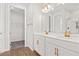 Bathroom with double sinks, white cabinetry, bronze hardware and wood-look tile floor at 1635 Sugarbelle Cir, Mascotte, FL 34753