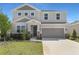 Charming two-story home featuring a manicured lawn, stone accents, and a two-car garage at 1635 Sugarbelle Cir, Mascotte, FL 34753