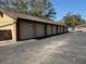 A row of individual garages with tan doors, brick accents, and a paved driveway at 300 New Waterford Pl # 204, Longwood, FL 32779