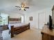 Comfortable bedroom featuring a wooden bed frame, neutral carpet, and ceiling fan at 3075 Barbados Ln, Haines City, FL 33844