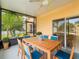 Enclosed patio with a wooden table, blue chairs, ceiling fan, and view of the backyard at 167 Bell Tower Xing W, Poinciana, FL 34759