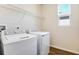 Bright laundry room with a modern, white washer and dryer set, a wire shelf, and a window at 636 Hennepin Loop, Lake Wales, FL 33898