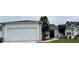 Front view of a single story home with a white exterior, attached garage, and landscaping at 325 Ashley Loop, Davenport, FL 33837