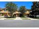 A sunny daytime shot of a tan two-story townhome with a front lawn and a tree-lined street at 721 Interlude Ln # 105, Orlando, FL 32824