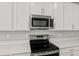 Stainless steel range and microwave installed above in white kitchen cabinets at 930 Heirloom Dr, Haines City, FL 33844