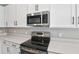 Stainless steel microwave and range sit above white cabinets in this kitchen at 1446 Maddie Berry Ln, Kissimmee, FL 34744