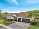 Charming home with a tile roof, brick driveway, mature palm trees, and lush, green grass at 2891 Swoop Cir, Kissimmee, FL 34741