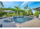 Inviting swimming pool with patio furniture, umbrella, and lush greenery at 2891 Swoop Cir, Kissimmee, FL 34741