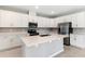 A modern kitchen featuring white cabinets, stainless steel appliances, a central island, and sleek countertops at 4220 Sawtooth Ct, Tavares, FL 32778