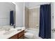 Bright bathroom features tiled walls, tub with shower, dark blue shower curtain and vanity with marble countertop at 14121 Bella Ln, Orlando, FL 32832