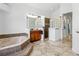 Bright bathroom featuring a soaking tub, glass block accent wall, tile floors, and a wood vanity at 14121 Bella Ln, Orlando, FL 32832