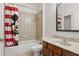Bright bathroom features tiled walls, tub with shower, Mickey Mouse shower curtain and vanity with marble countertop at 14121 Bella Ln, Orlando, FL 32832