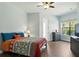 Well-lit bedroom with wood floors, large windows, a ceiling fan, and colorful bedding at 14121 Bella Ln, Orlando, FL 32832