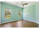 Bright bedroom with a ceiling fan, wood floors, two windows overlooking a lush green landscape at 14121 Bella Ln, Orlando, FL 32832
