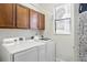 Laundry room featuring new white washer and dryer and wood cabinetry above machines and blinds on the window at 14121 Bella Ln, Orlando, FL 32832