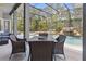 Covered patio with a dining table set, overlooking a screened-in pool with waterfall at 14121 Bella Ln, Orlando, FL 32832