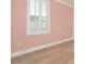 A bedroom featuring a pink wall, wood floors, a window with shutters, and white trim at 1862 Beach Ridge Rd, Celebration, FL 34747