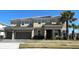 Two-story tan home with a two-car garage, a tiled roof, a well-manicured lawn, and a palm tree in the front yard at 3801 Sonoma Blvd, Kissimmee, FL 34741