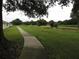 Exterior view of property featuring green grass, concrete pathway, and mature trees at 2724 Shelby Ruth Pl, Saint Cloud, FL 34769