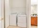 A well-lit laundry room features a washer and dryer, with shelving, next to a full bathroom at 2106 Chatham Place Dr, Orlando, FL 32824