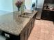 This kitchen island boasts granite countertops, double sinks and dark cabinetry, next to stainless steel appliances at 4183 Cortland Dr, Davenport, FL 33837