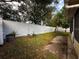 Well-maintained backyard featuring mature trees, a brick pathway, and a secure white fence at 5906 Rywood Dr, Orlando, FL 32810
