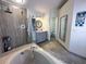 Bathroom featuring gray cabinets, glass shower with stone tile and a large soaking tub at 5906 Rywood Dr, Orlando, FL 32810