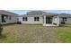 Residential backyard with a covered patio, grassy lawn, and partial view of surrounding houses on a sunny day at 1647 Sugarbelle Cir, Mascotte, FL 34753