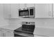 Modern kitchen featuring stainless steel appliances, white cabinets, and white quartz countertops at 1647 Sugarbelle Cir, Mascotte, FL 34753